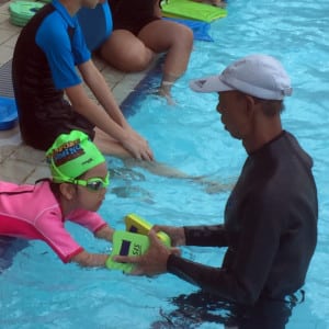 Child learning to swim with instructor at Singapore Swimming Academy